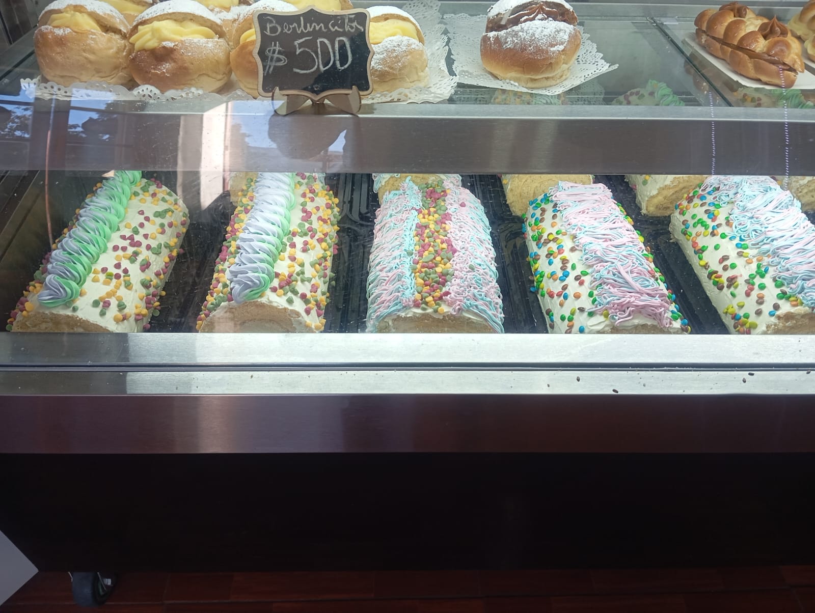 Berlines horneados de crema pastelera junto a brazos de reina en la vitrina