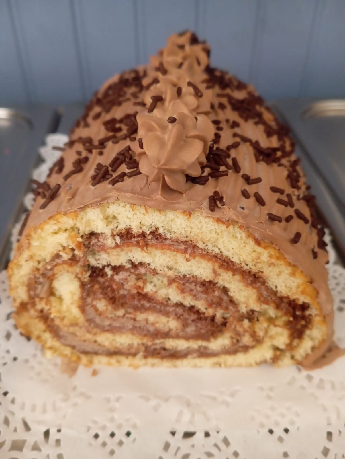 Brazo de reina relleno y cubierto de chocolate con chispas