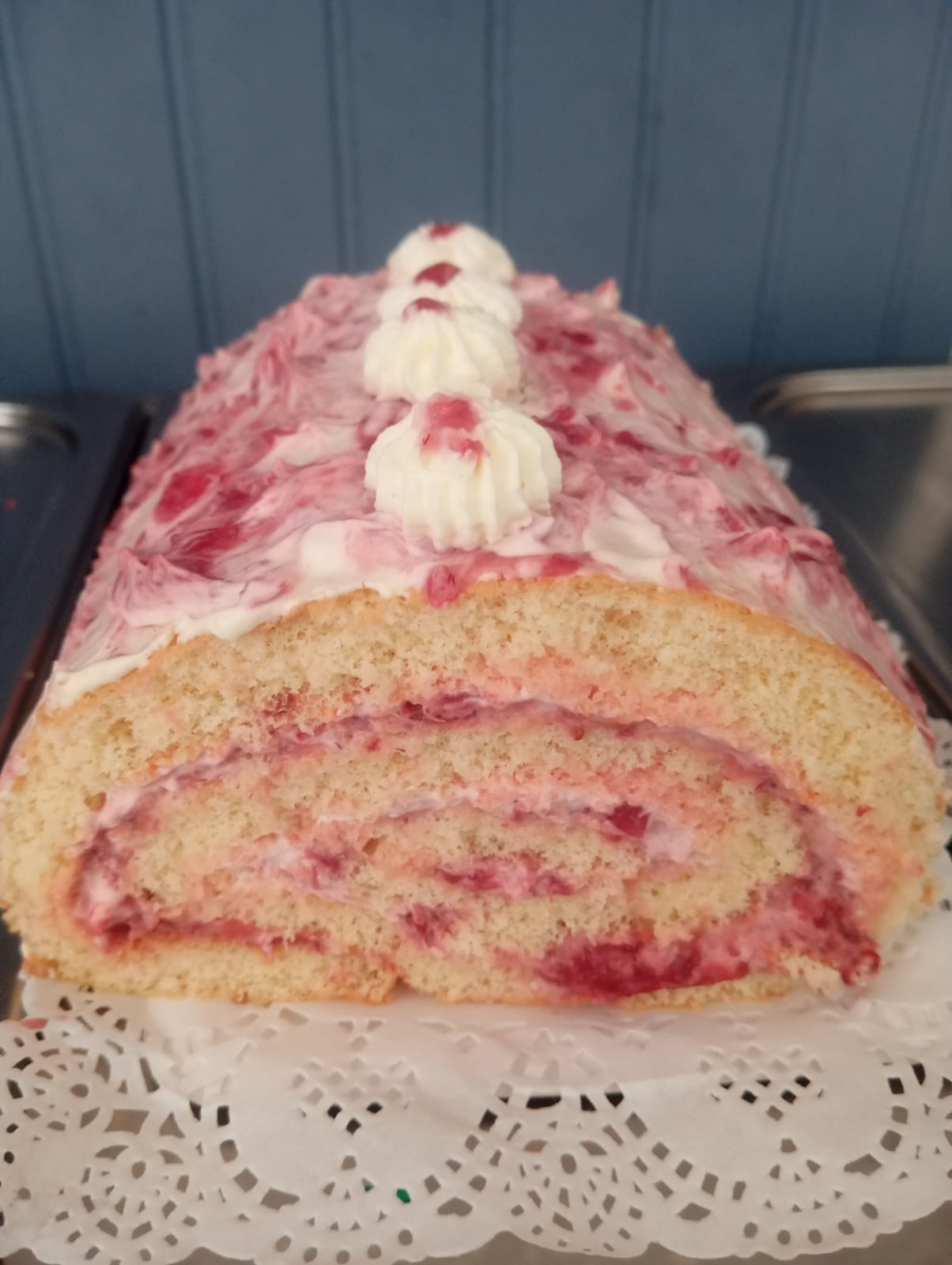 Brazo de reina de frambuesa con crema y trozos de fruta natural